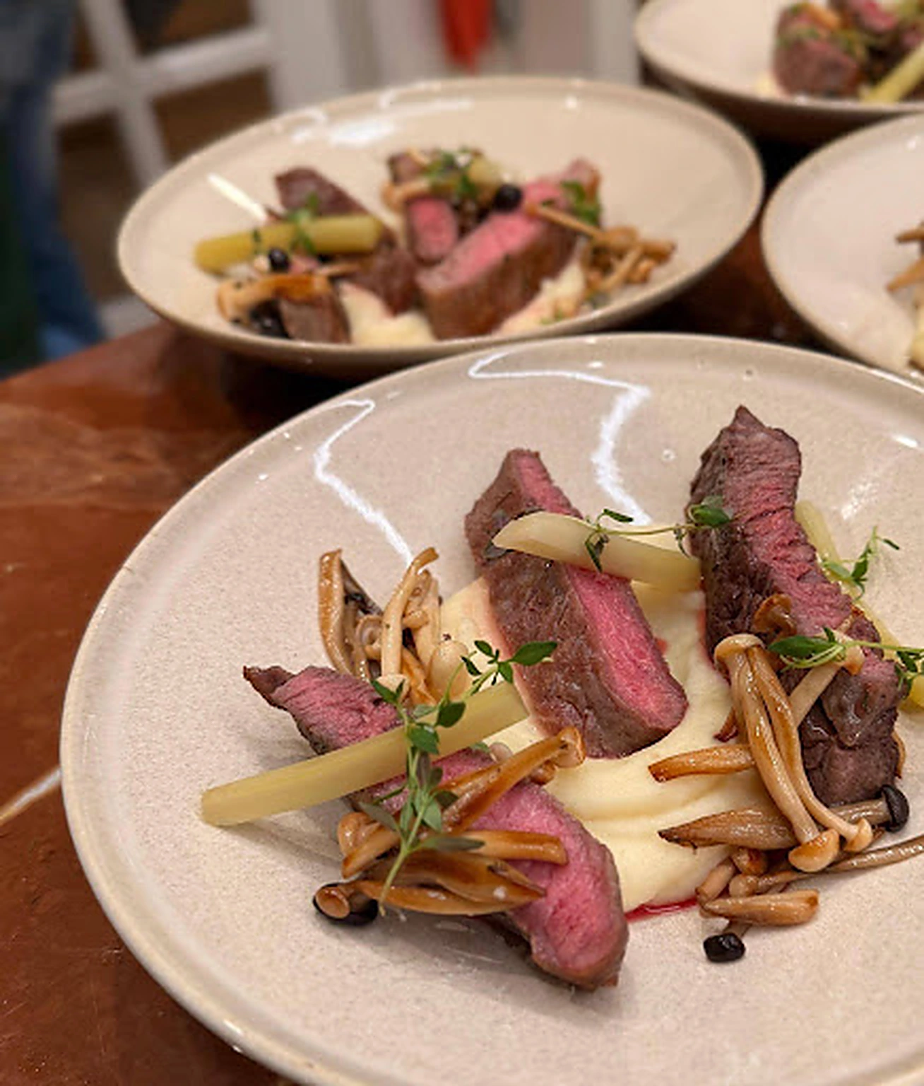 Plates of pink beef with mushrooms and vegetables ready to serve