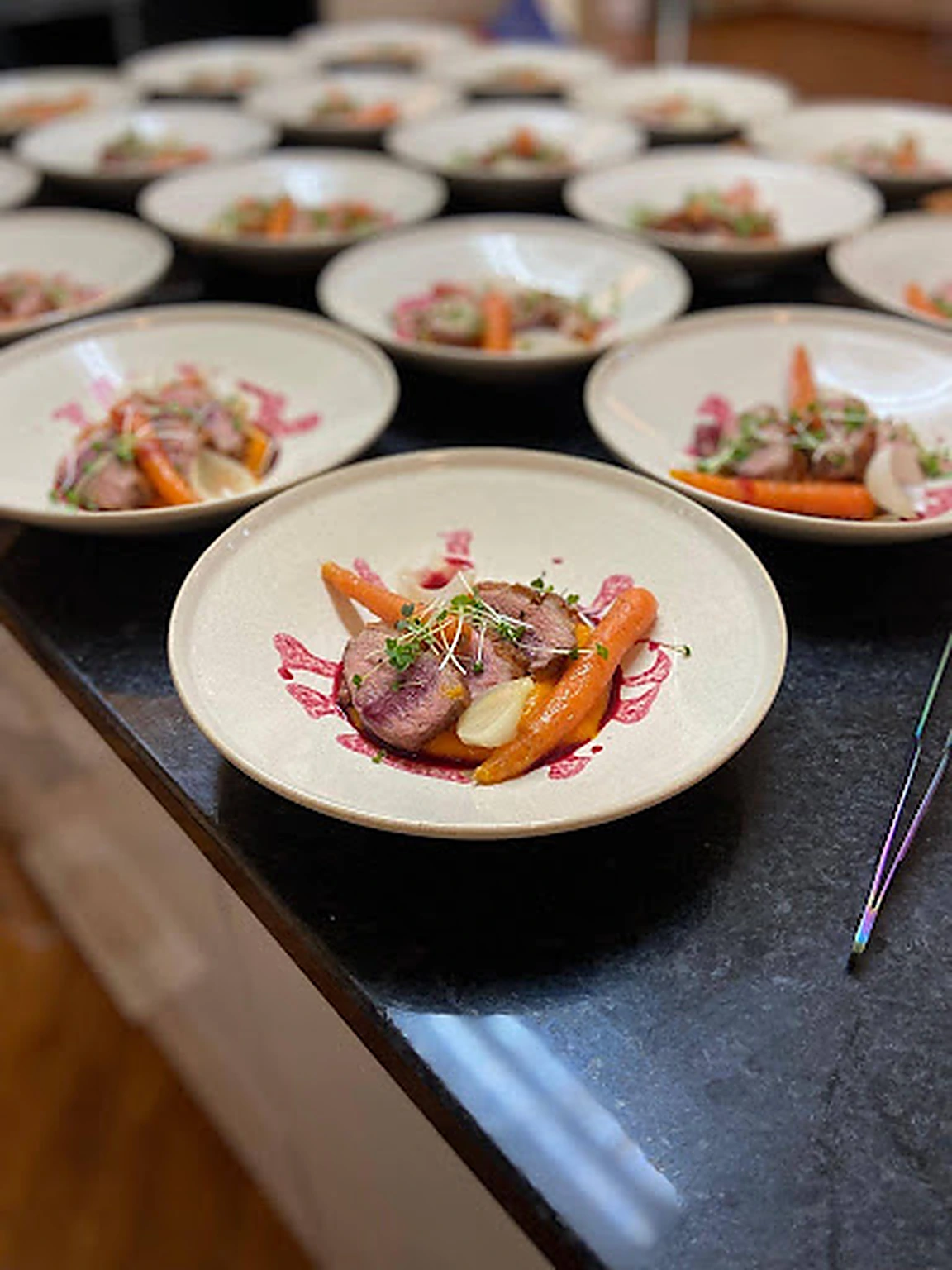 A row of plated courses with glazed carrots and seasonal garnish