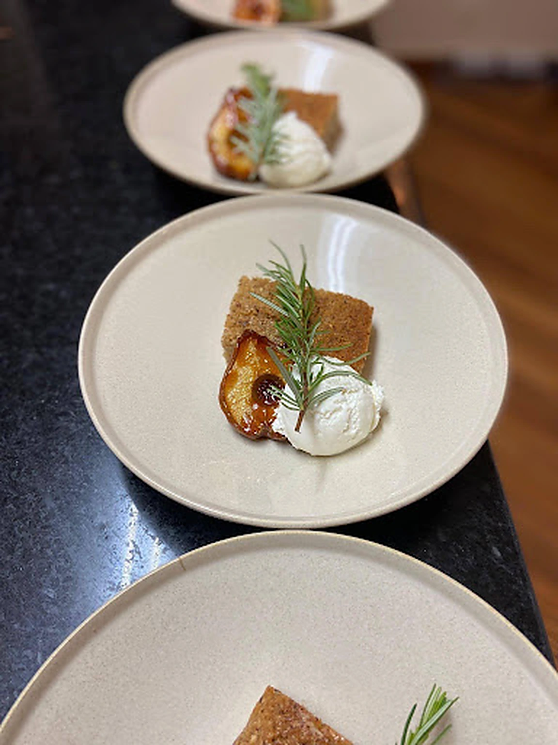 Plated fruit dessert with cream and rosemary prepared for Basil service