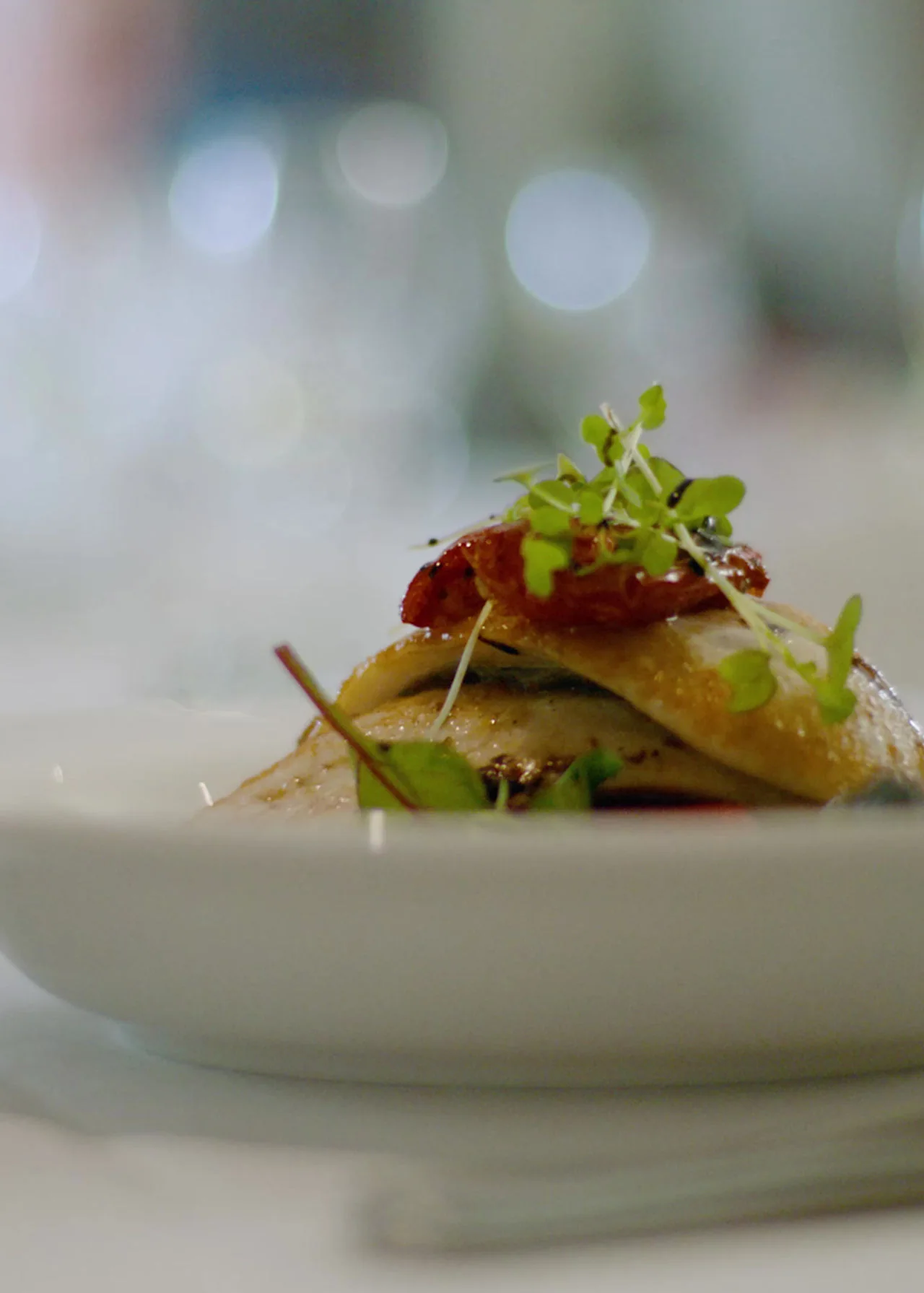 A plated course finished with micro herbs in a pale ceramic bowl at a private dinner in the Algarve