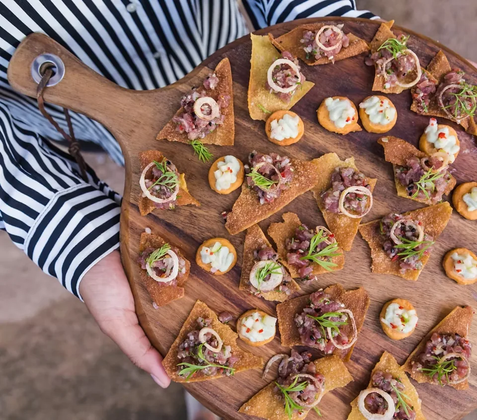 A board of canapés with beef tartare and whipped cheese carried at an Algarve catering event